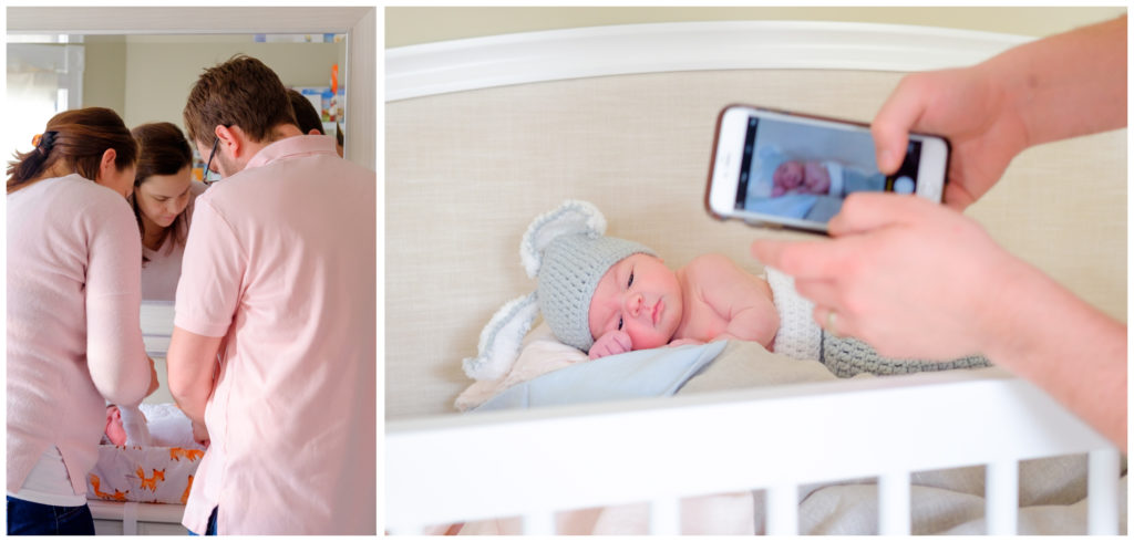 new mom and dad changing their newborn and baby in a bunny costume in her crib while dad takes a cell phone picture