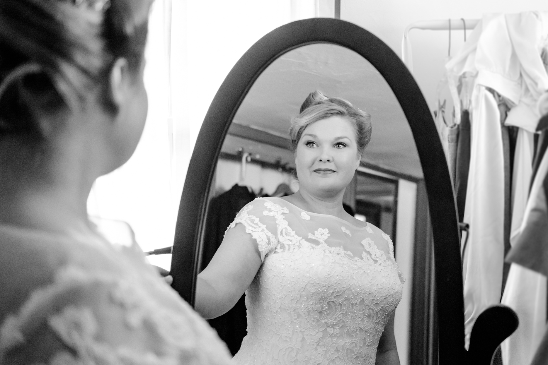 Bride looks into a mirror while getting ready in the historic house of the seven gables in salem massachusetts. This elopement has a classic pin up style with a tea length dress and gorgeous curls in her hair. This North Shore elopement was an intimate wedding and it was an honor to be the photographer for this couple.