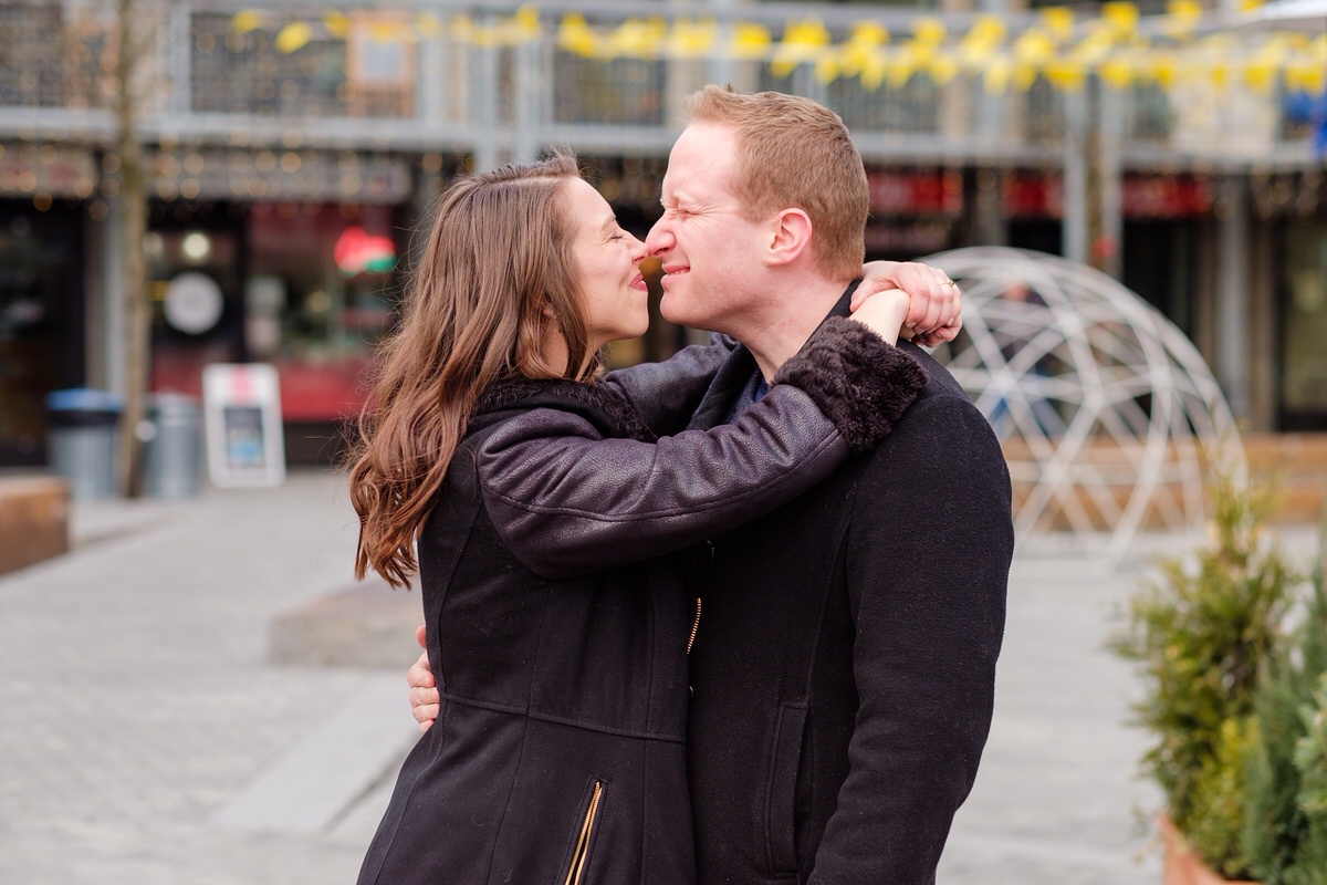 Engaged couple nuzzling at Bow Market in Union Square