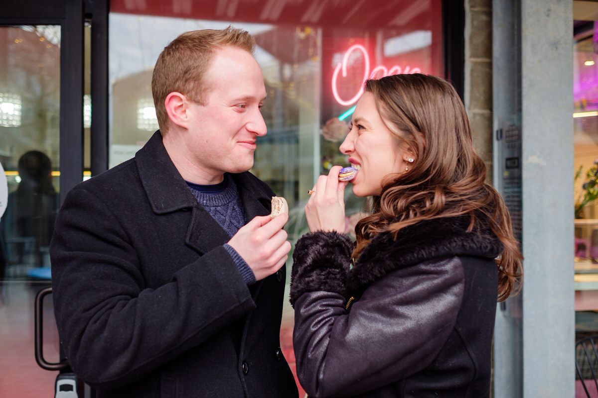 Engaged couple eating macarons in Bow Market in Union Square