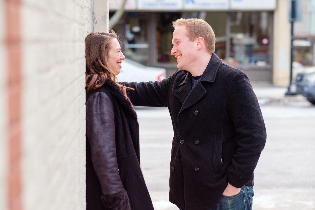 Engaged couple standing against a grey wall at Bow Market in Union Square