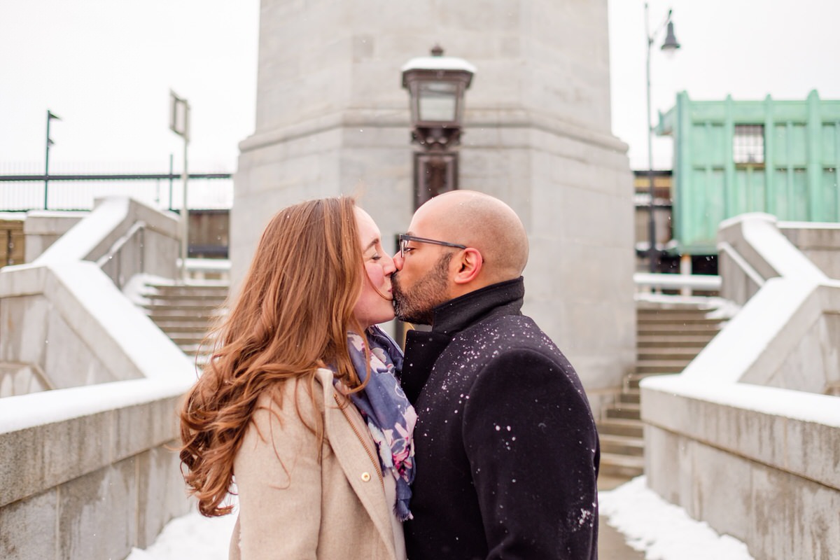 Engaged couple kisses on the steps of the Longfellow Bridge in front of the Charles MGH red line T stop in Boston.