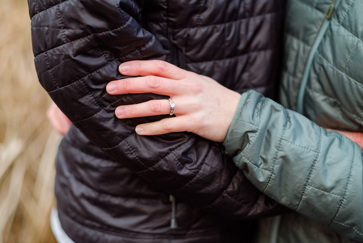 Woman holds her partner's arm with engagement ring in view