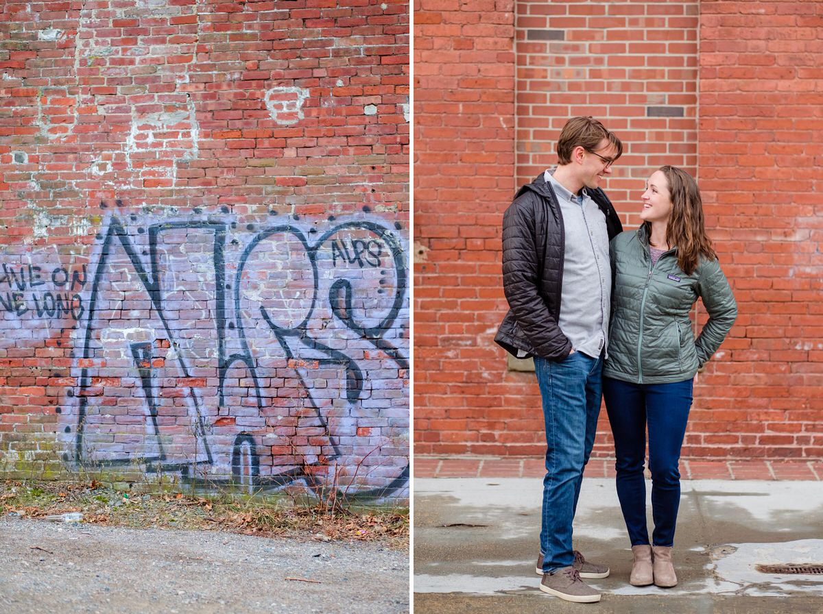 Engaged woman in a coat holds her fiance in front of a brick wall with graffiti during a winter engagement session in Davis Square