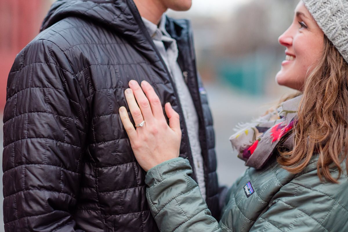 Woman places her hand with engagement ring on fiance's chest during winter photoshoot