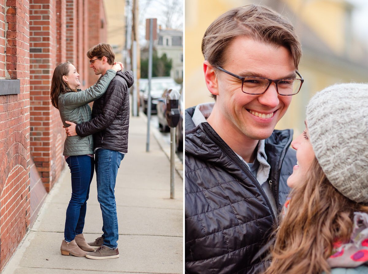 Couple in coats dance by a brick wall during a winter engagement session in Somerville, MA