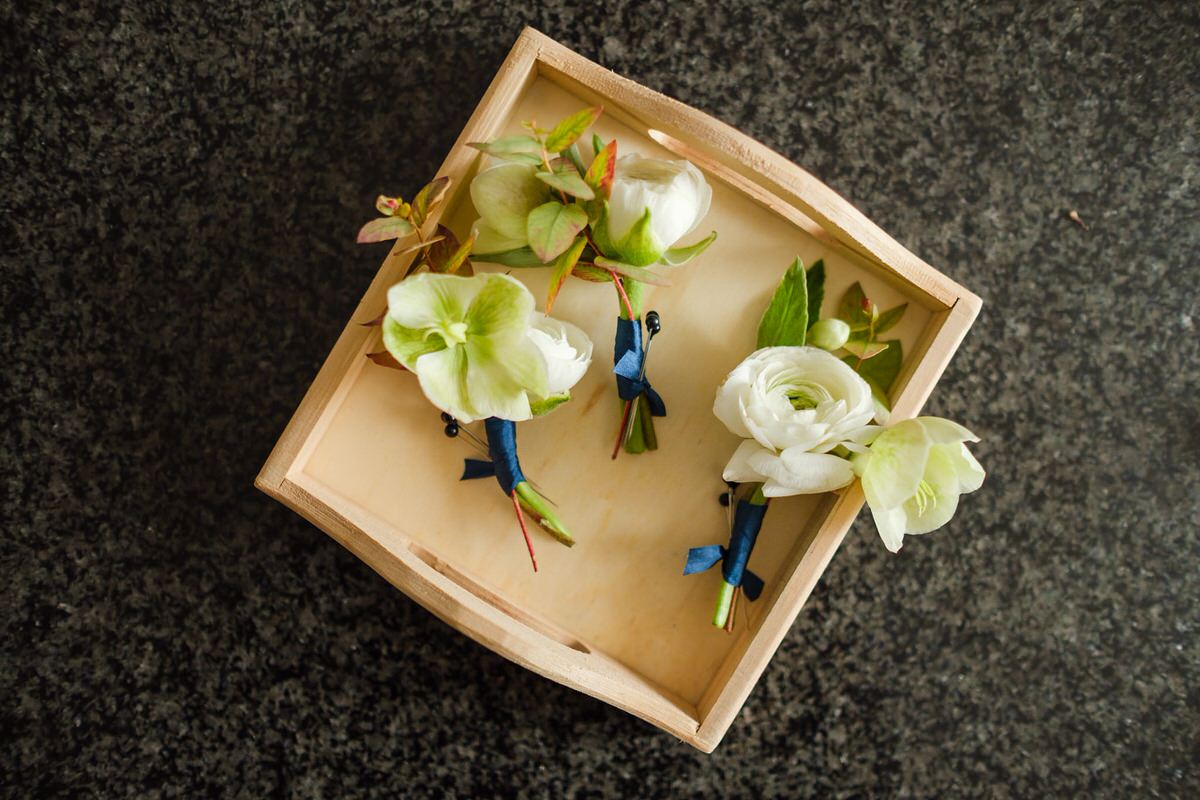 White ranunculus boutonnieres in a wooden box