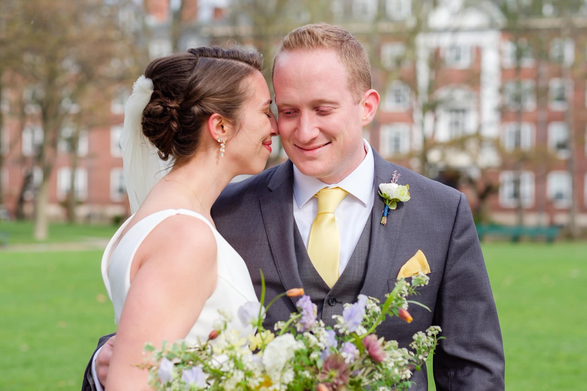 Bride in white nuzzles nose to her future husband's cheek