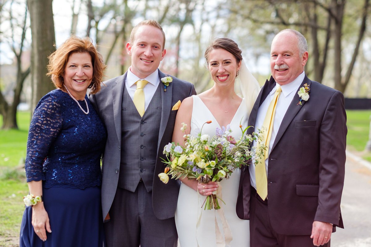 Bride and groom pose for formal portrait with the groom's family