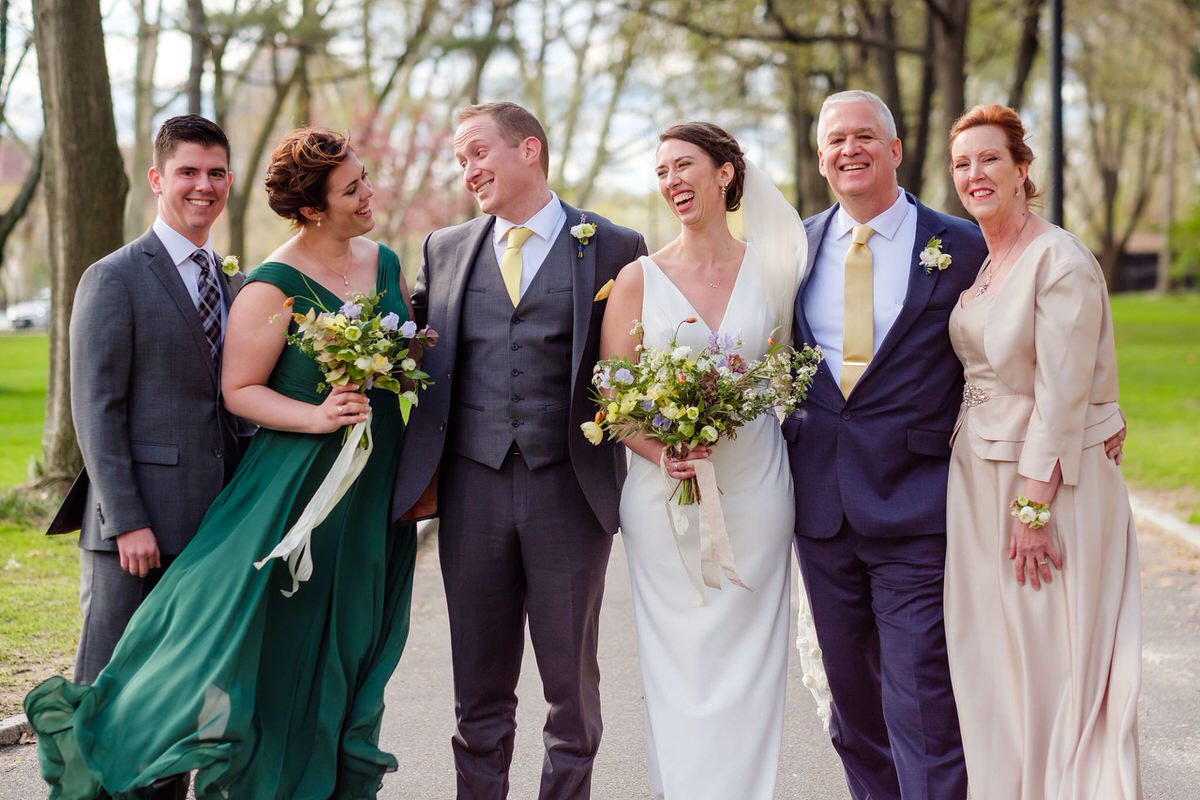 Bride and groom smile at her family members in formal portrait