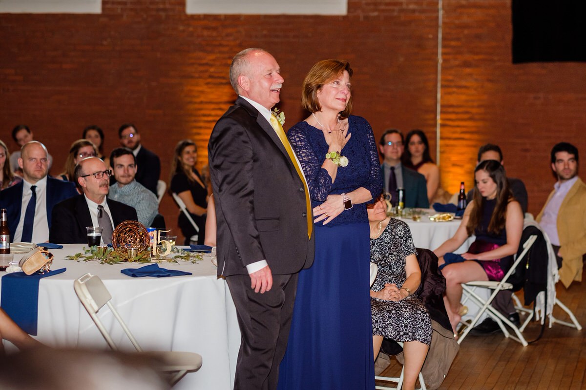 Groom's parents look on as the groom reads them a message