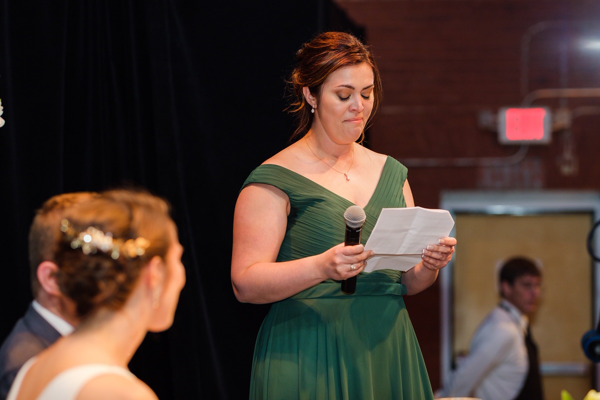 Bridesmaid in a green dress reads her wedding toast