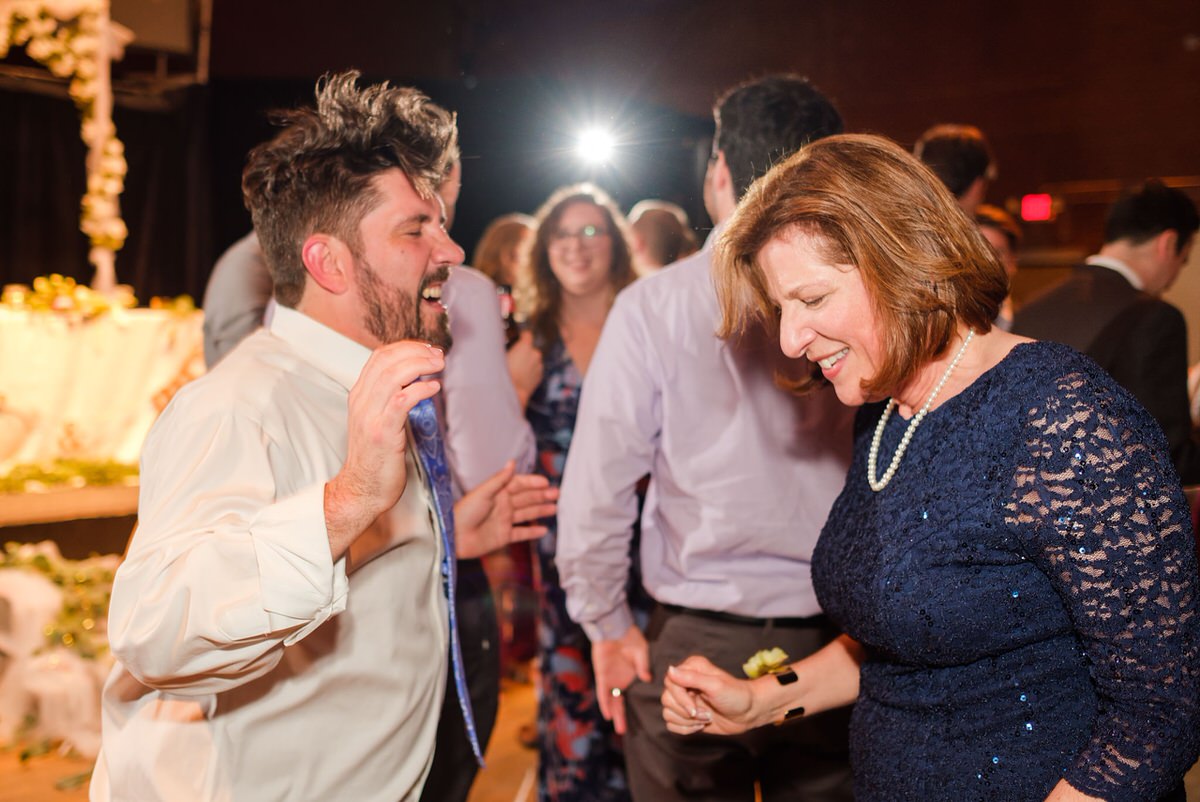 Groom's mom dances with a family member whose hair is flying