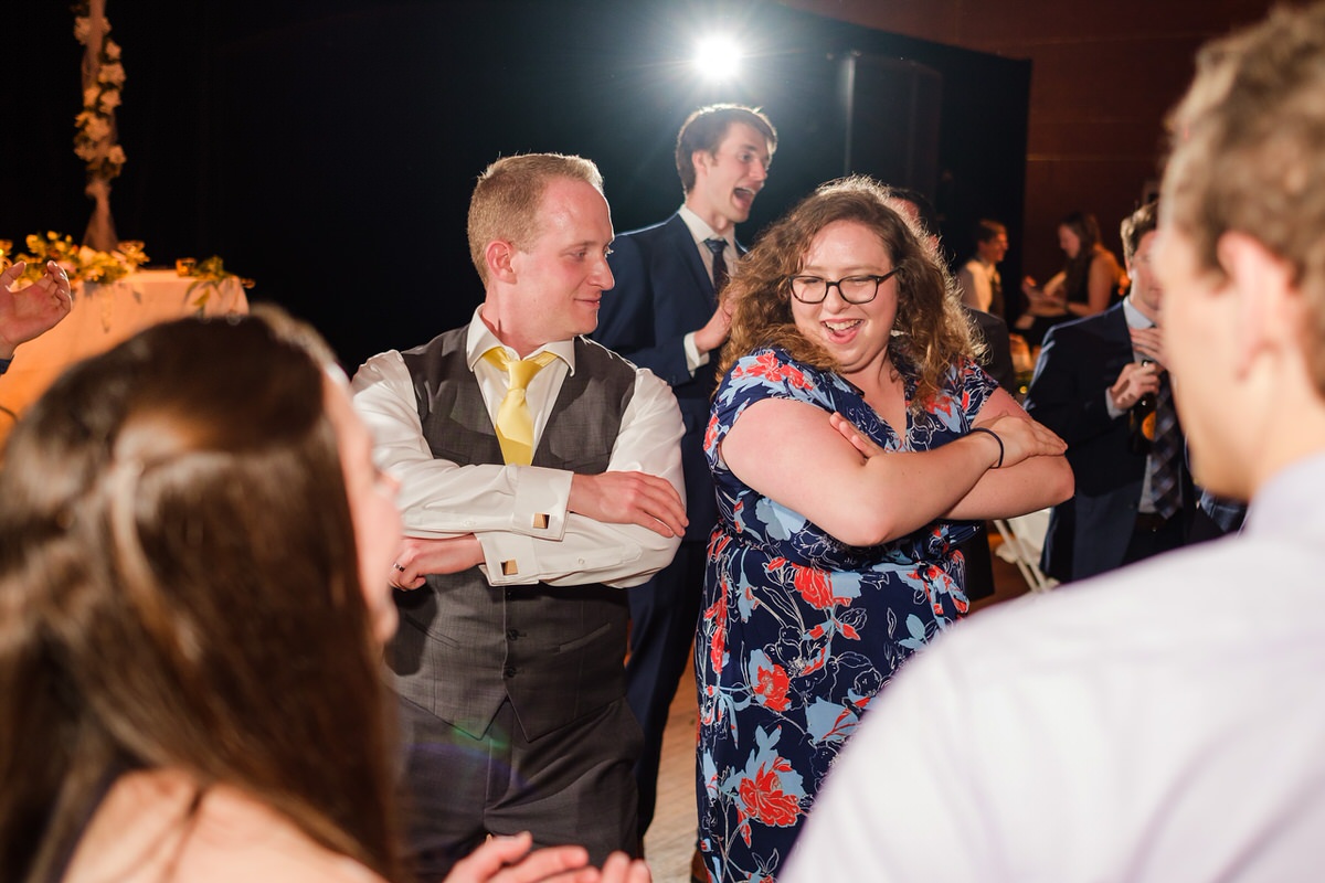 A guest dances back to back with the groom with crossed arms