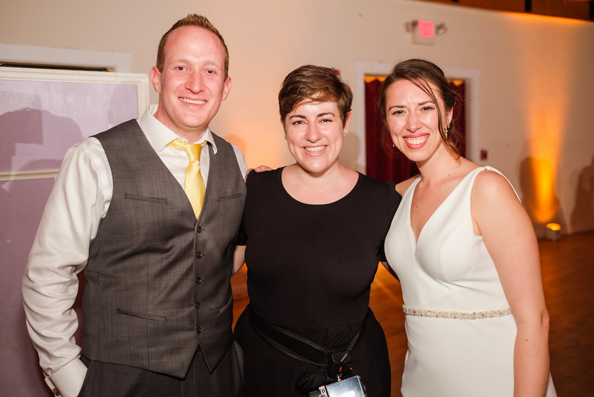 Bride and groom smile and pose for a picture with Golden Door Photography owner Shaina