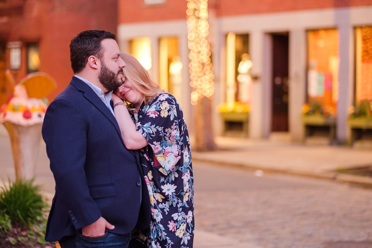 A woman lays her head on her partner's chest as they stand near the road at night in Salem, MA