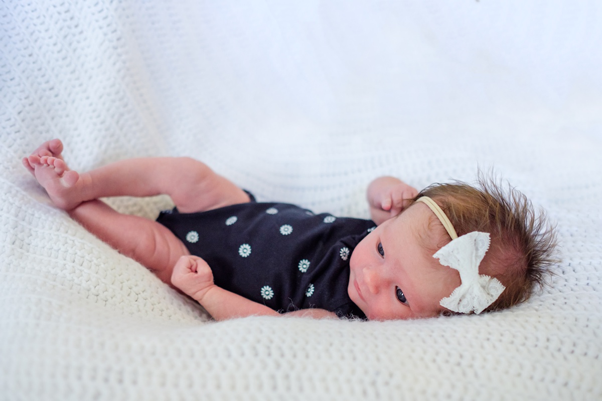 Newborn girl with a white bow and navy onesie