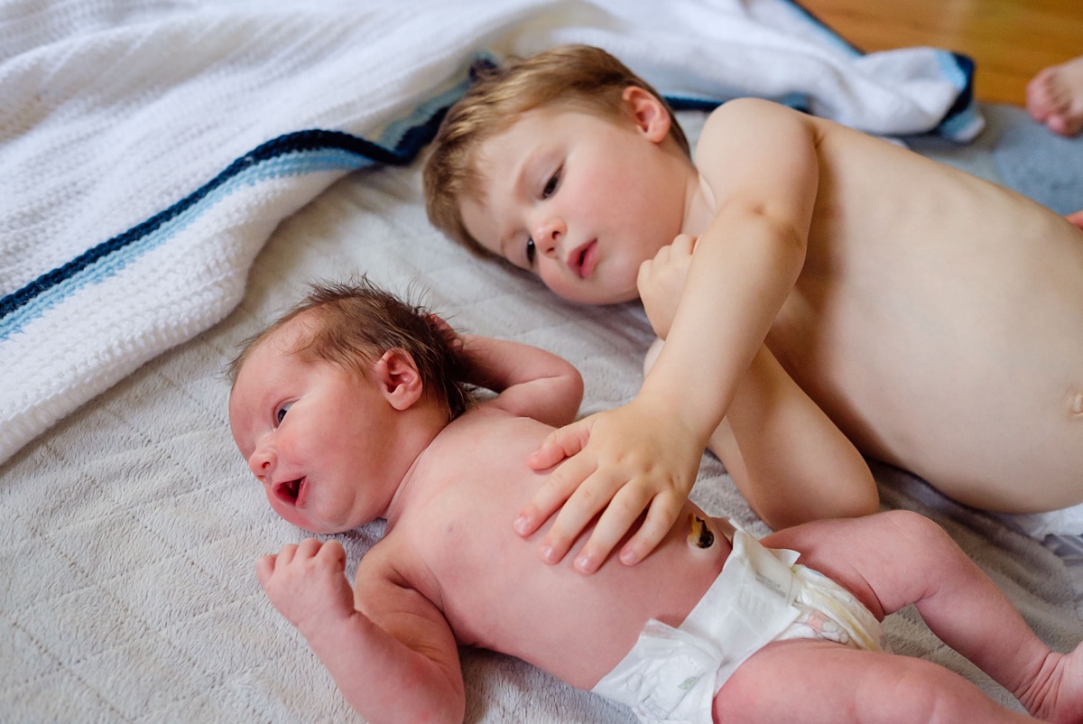 Newborn and two year old in diapers on a blanket