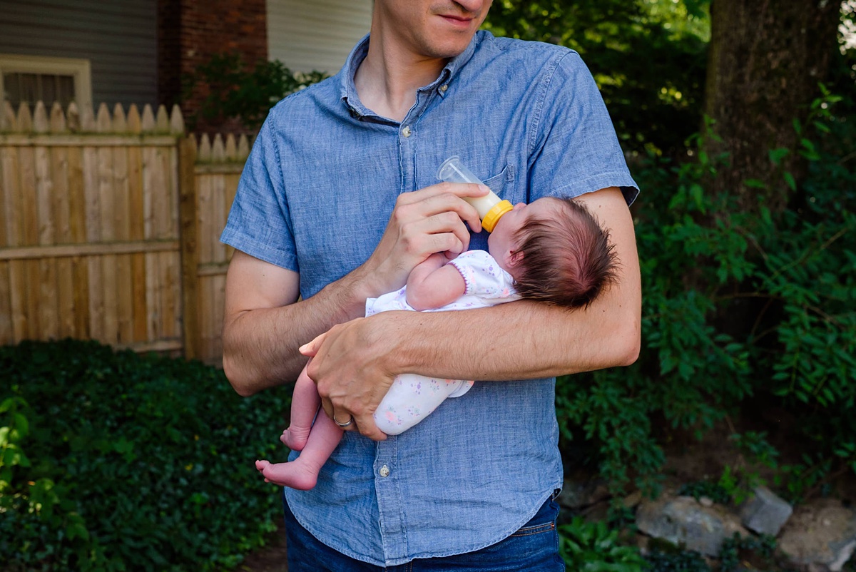 Dad bottle feeds his newborn daughter