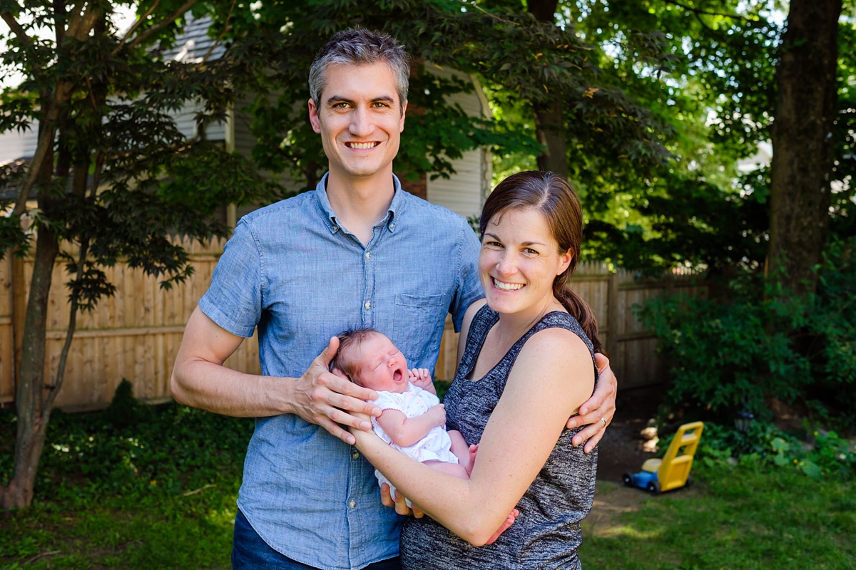 Mom and Dad hold yawning newborn baby girl