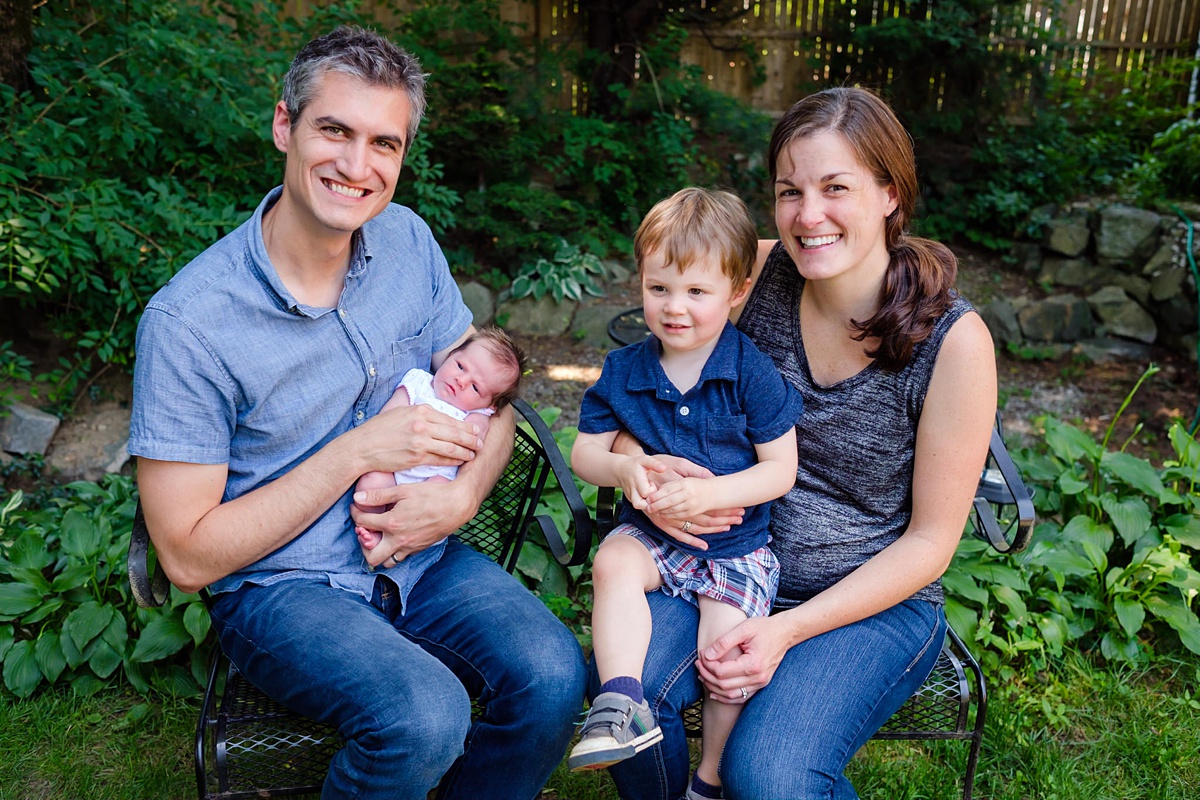 Mom, Dad, toddler boy and newborn girl smile in family portrait