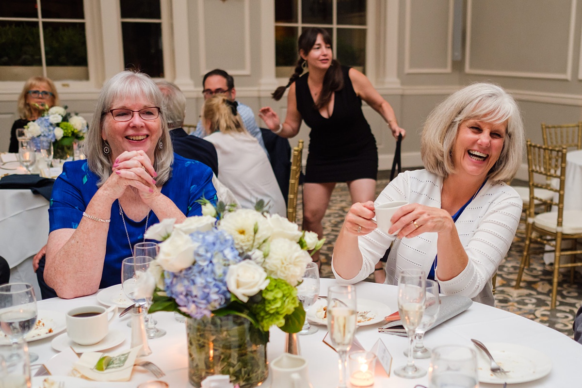 Two wedding guests laugh as another dances behind them