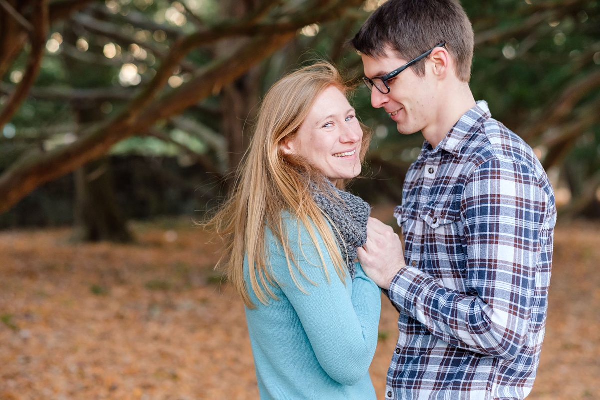 Windblown woman smiles as her fiance warms her hands in a park in Boston