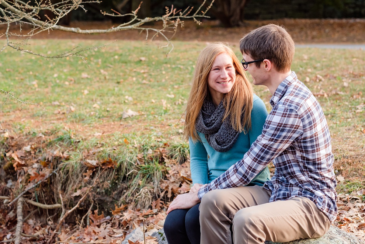 Engaged couple sits by a river at the Arnold Arboretum in Jamaica Plain