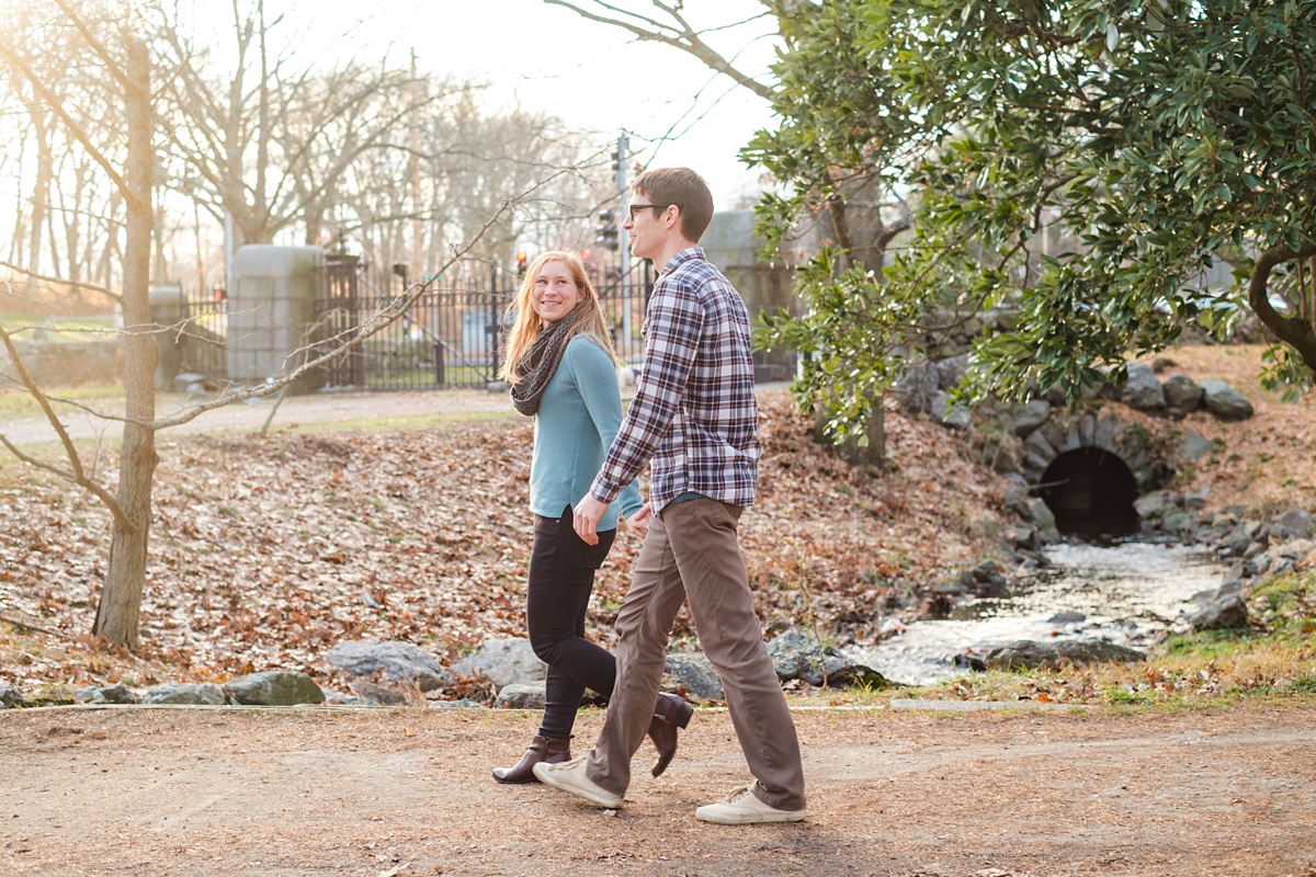 Engagement photo of a couple walking over a bridge in the Arnold Arboretum