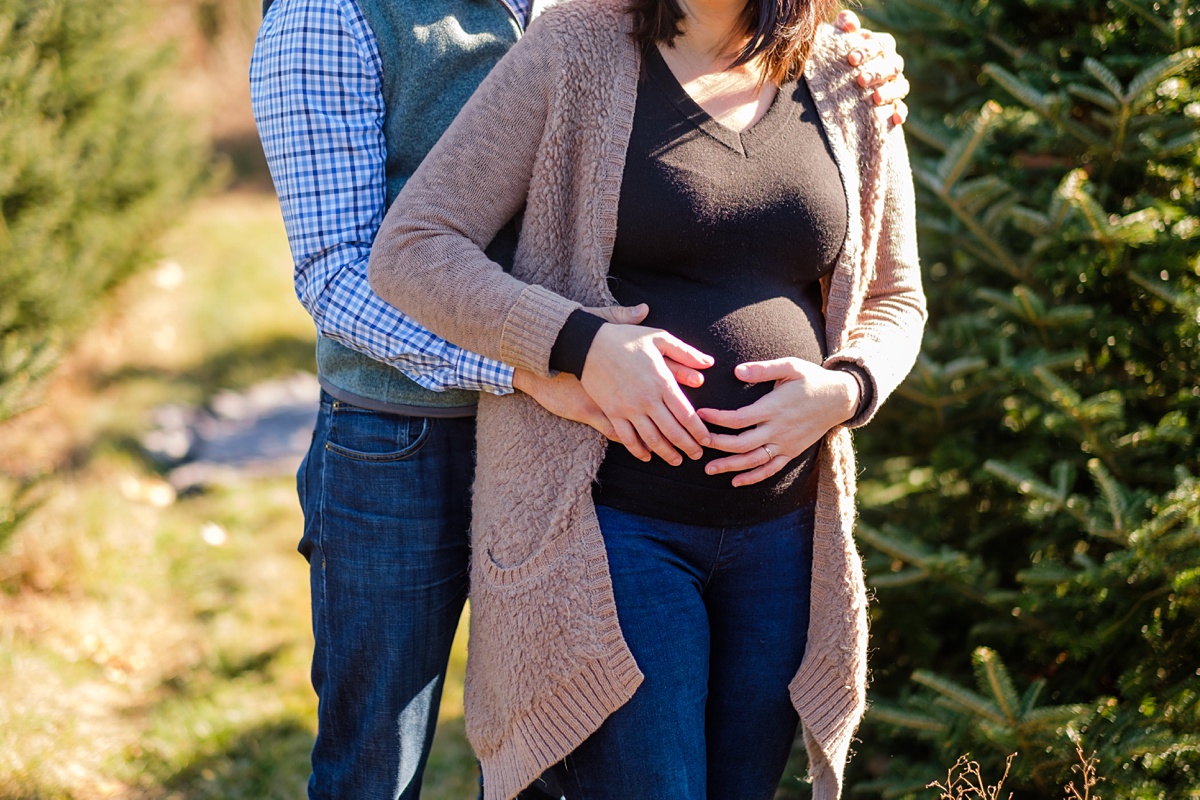 Christmas tree farm maternity photo shoot holding belly