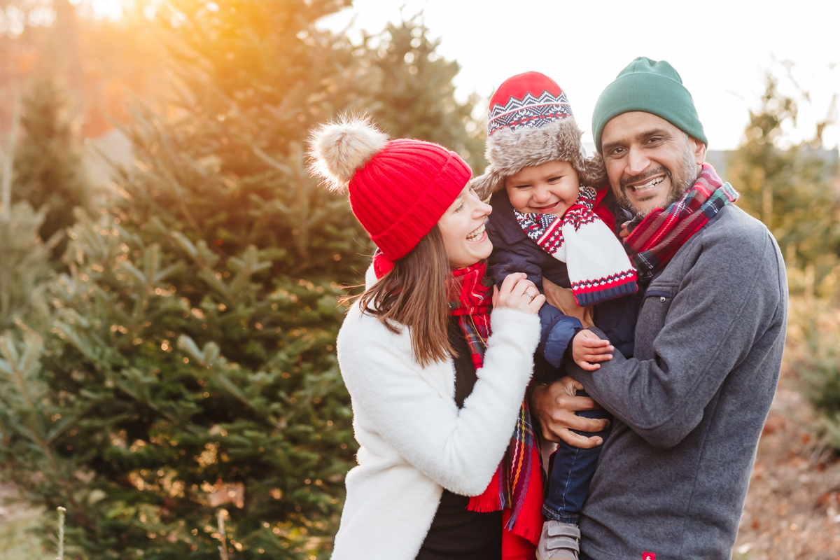 Multi-ethnic family cuddles in beanies and scarves at a holiday mini photoshoot in Topsfield, MA