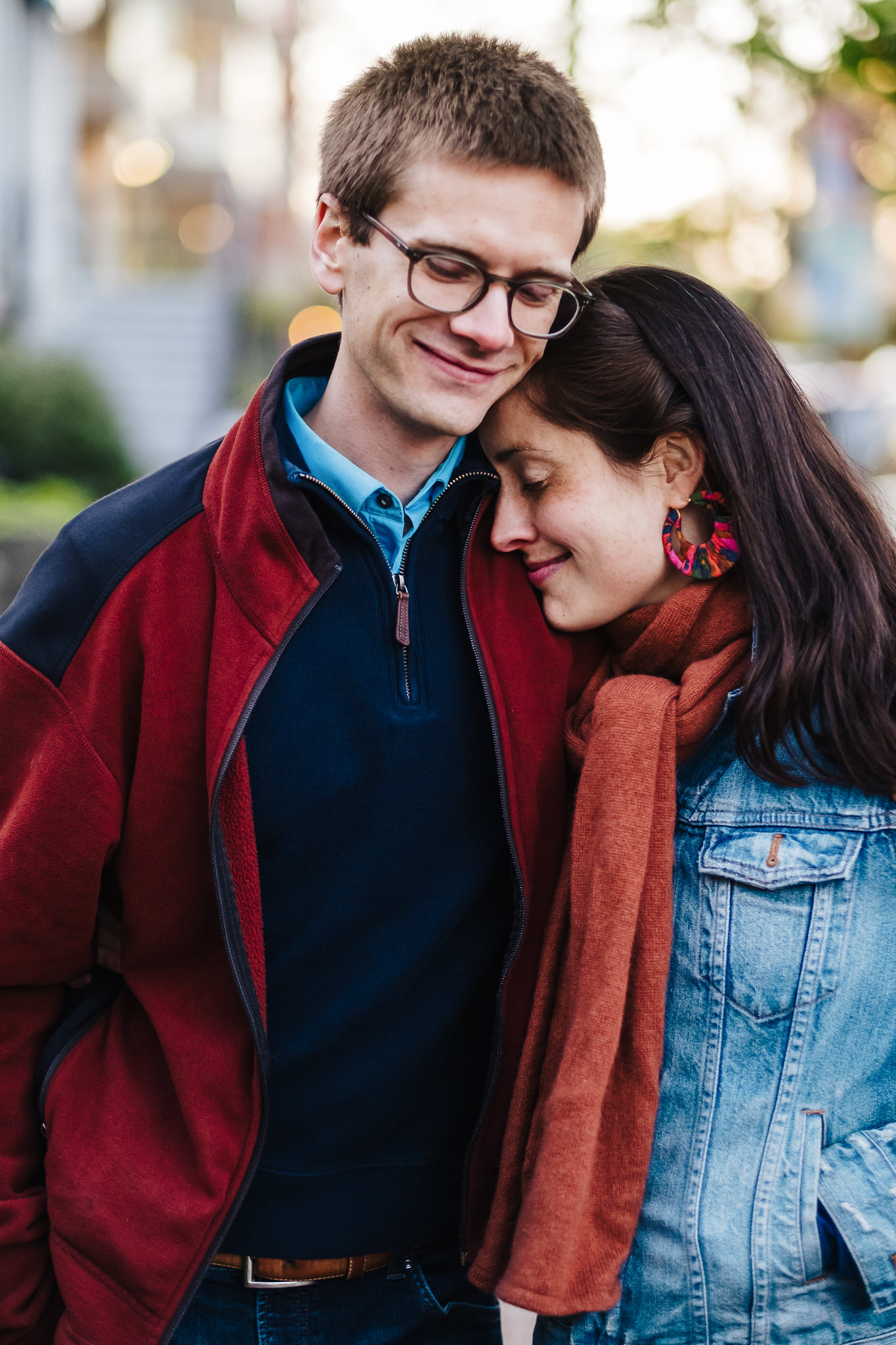 Engaged white couple nuzzles together in a close up in Harvard Square