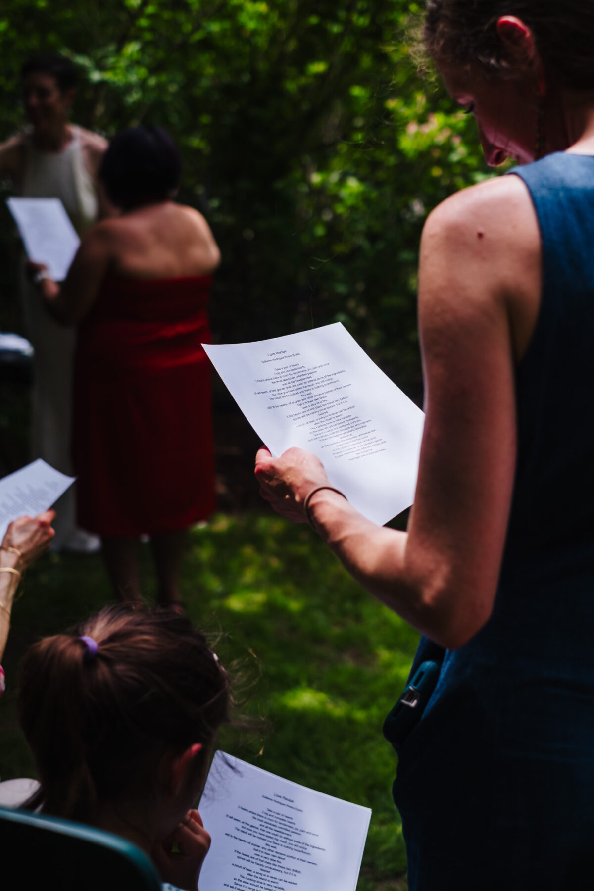 A translated Spanish reading is held by a backyard wedding guest.