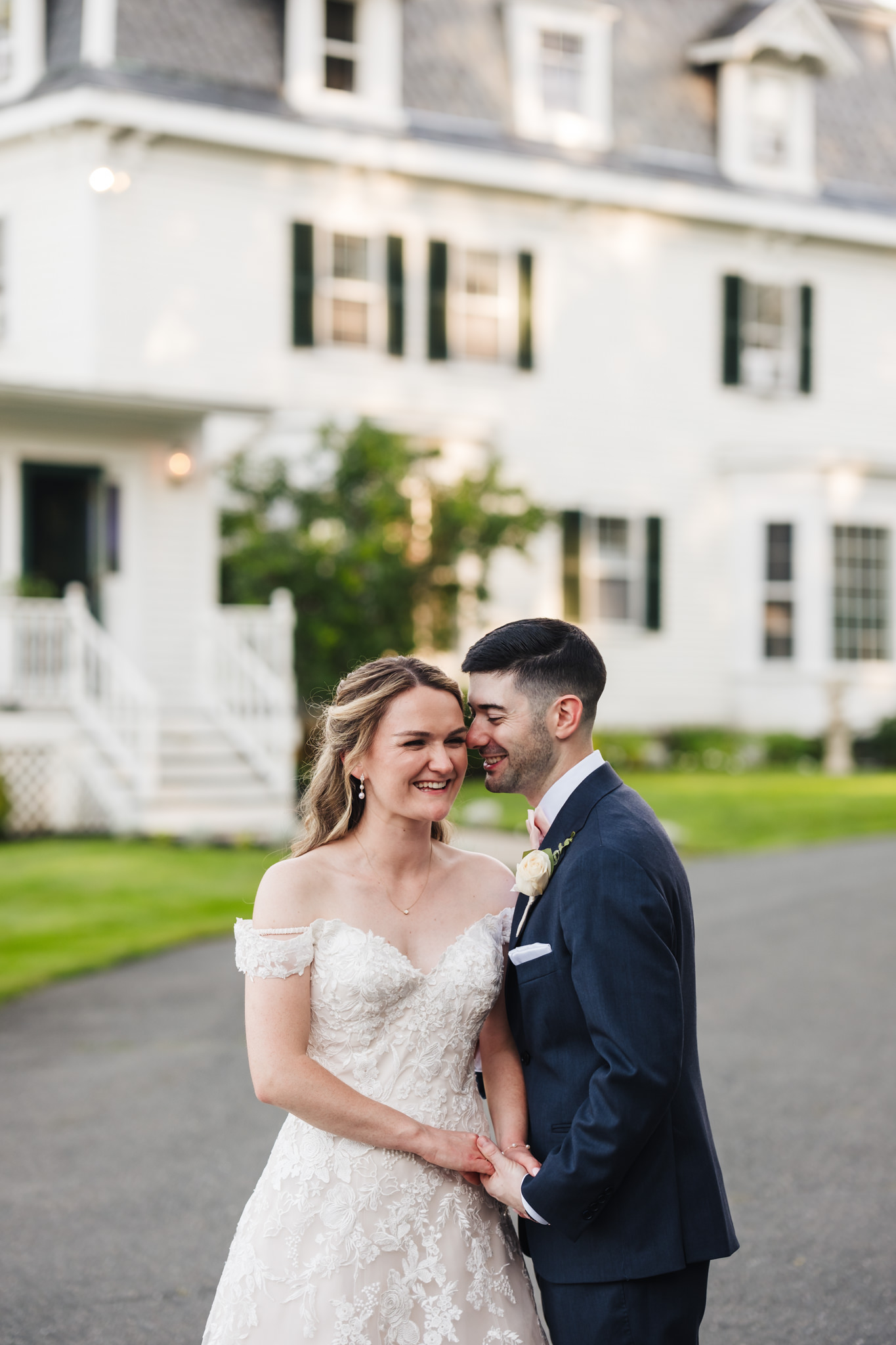 Groom nuzzles bride outside a manor at Peirce Farm at Witch Hill