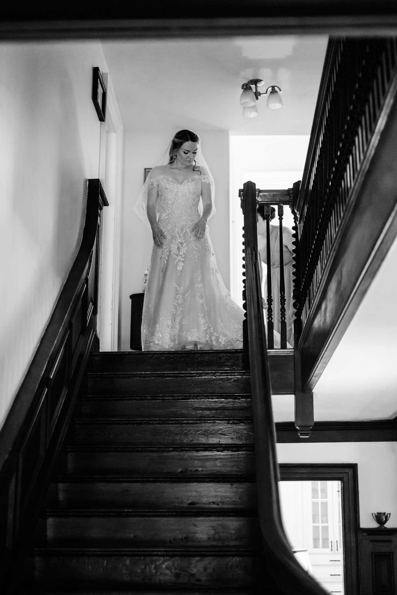 Bride in white dress descends manor staircase at Peirce Farm at Witch Hill