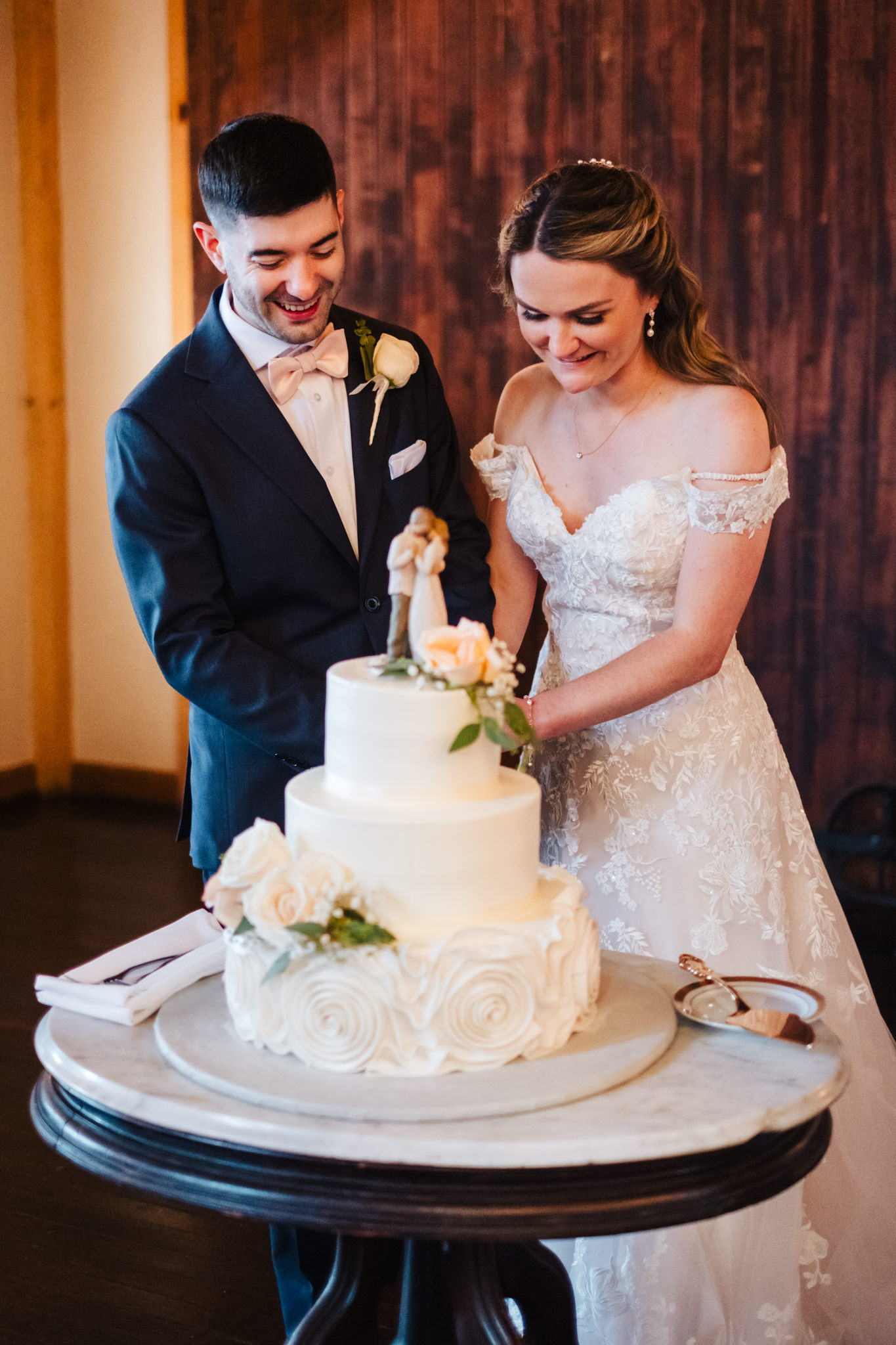 Bride and groom cut wedding cake in a barn at Peirce Farm at Witch Hill